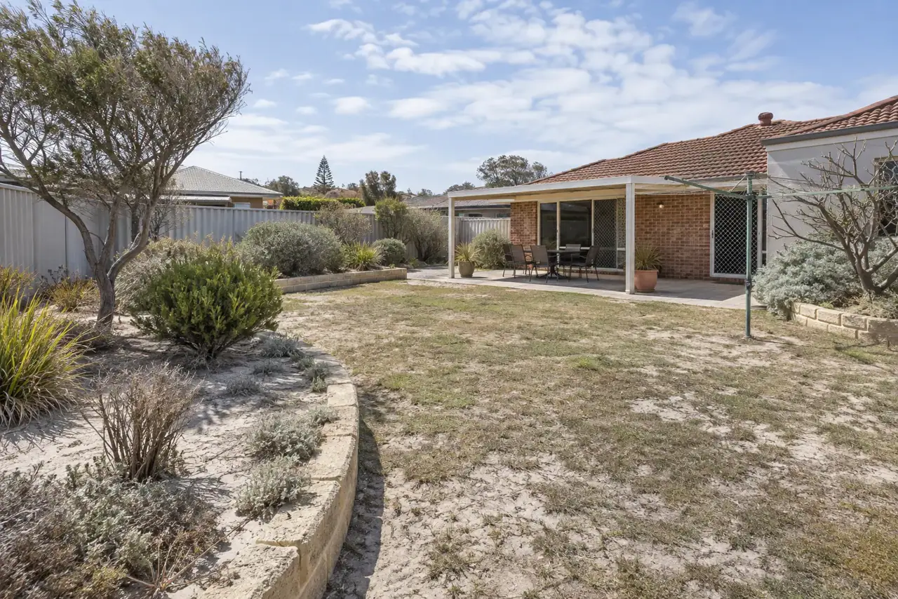 Established northern Perth backyard with pale exposed sand patchy lawn and tired garden beds
